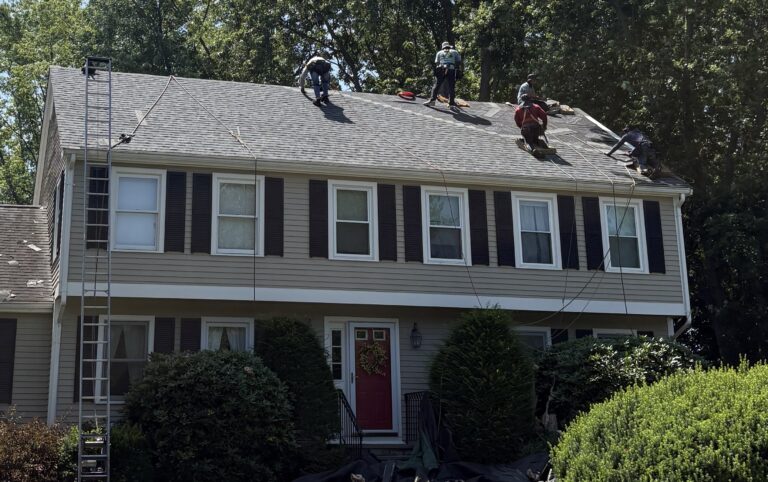 Roofers working on the rooftop of a house in Dover, Massachusetts.